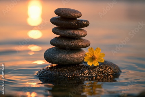 Balanced Zen Stones by Calm Water with a Yellow Flower