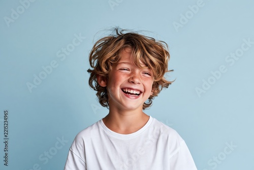 Happy Boy in a White T-Shirt Laughing on Light Blue Background