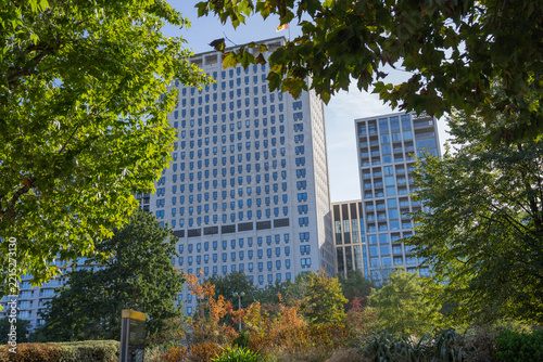 Image of the iconic Portland stone Shell Centre tower and modern high-rise buildings framed by lush park greenery from Jubilee Gardens on the South Bank, London.