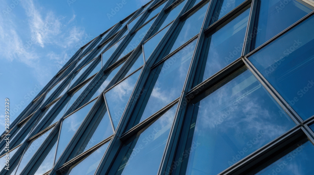 Obraz premium Modern glass skyscraper exterior showing dynamic architectural lines and sky reflections