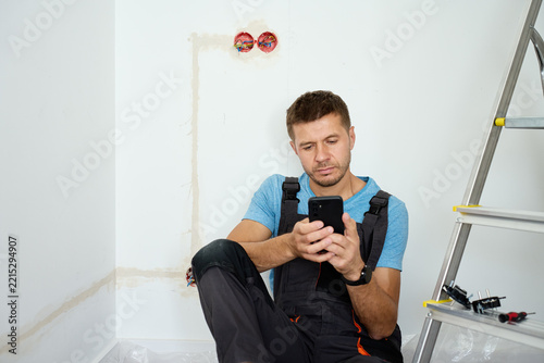 Man searching repair information on smartphone during renovation