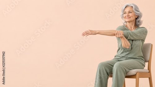 Senior woman practicing a gentle seated arm stretch against peach