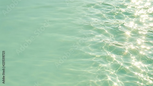Golden Sunlight Ripples Across Mint Green Water With a Calm Open Left Side