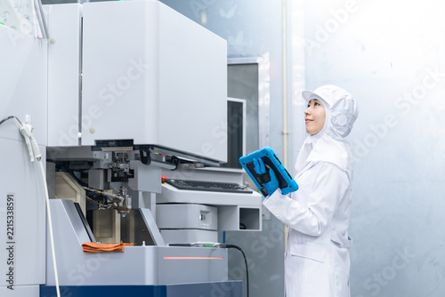 機械を操作する白衣の作業員。エンジニア、科学、実験、研究、開発、食品、製造業、工場、点検、検査、分析
