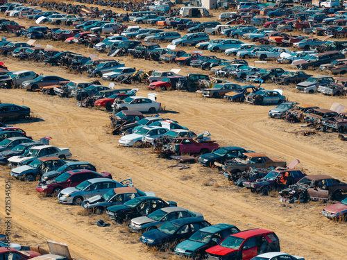 Aerial view of a vast automobile salvage and recycling facility with rows of discarded and damaged vehicles arranged on dry, dusty ground in Dacono, Colorado, United States.