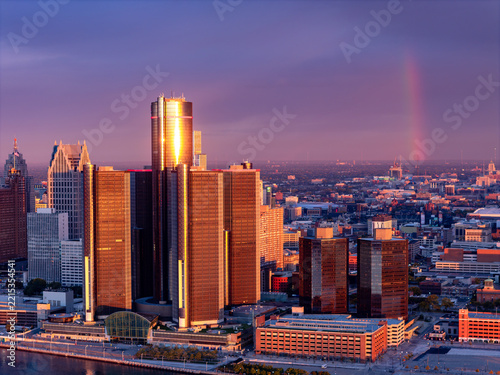 Aerial view of the Renaissance Center in Downtown Detroit illuminated by golden hour light with a faint rainbow over the city skyline in Detroit, Michigan, United States.