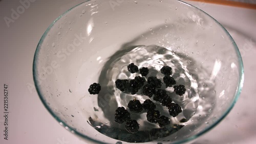 Dropping ripe blackberry fruit in a bowl of water