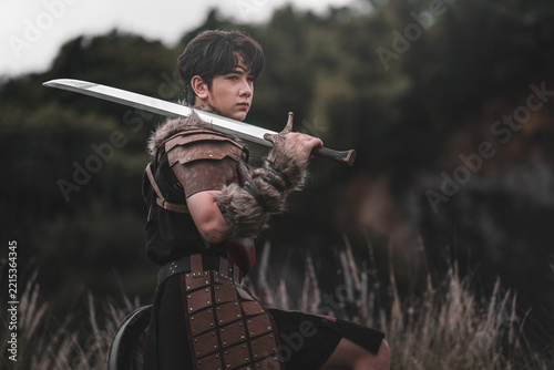 Brave Warrior in Armor Holding Sword in Dramatic Outdoor Setting