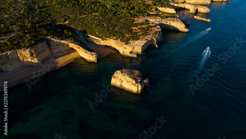 Picturesque coastal landscape of rugged limestone cliffs and clear turquoise water. Rocky cape over sea bay with stony shore under sunlight. Algarve, Portugal
