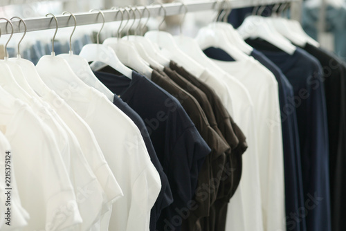 White, black and dark colored T-shirts hanging neatly on a clothing rack in a fashion store, casual apparel, minimalist fashion, shopping and clothing retail
