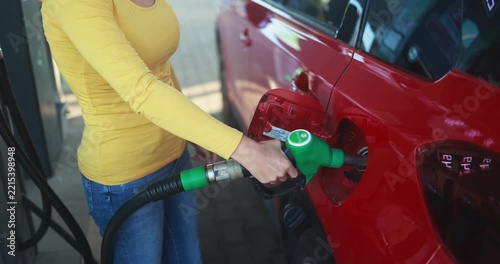 Woman pumping gasoline fuel in car at gas station - Inflation, transport and rising fuel prices concept - Focus on hand - UGC content