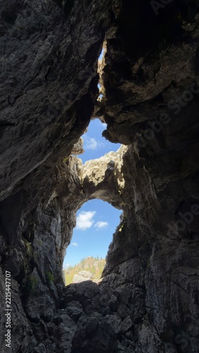 Unique limestone cave formation with blue sky view in rugged mountain wilderness