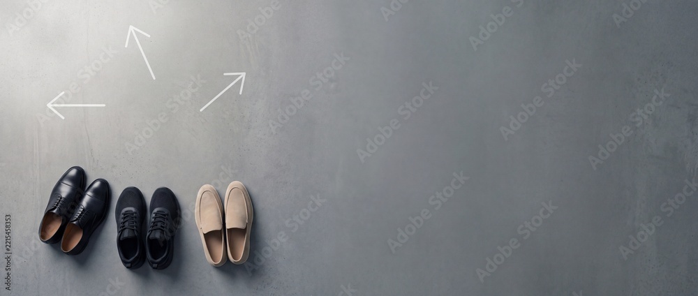Fototapeta premium Three Different Pairs of Shoes on Grey Concrete Background with Directional Arrows Representing Life Choices Career Paths and Decision Making with Ample Negative Space on the Right Side