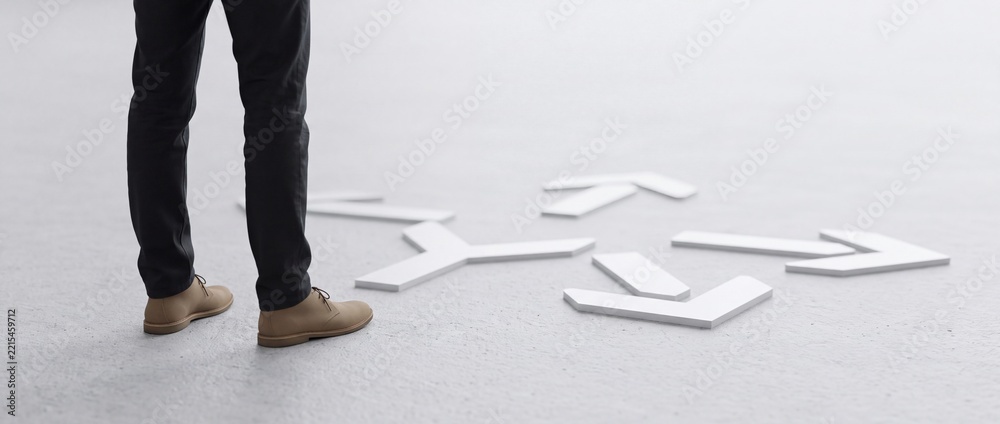 Fototapeta premium Close up of businessman legs standing at a crossroads of white directional arrows on a concrete floor, conceptualizing strategic decision making, career path choices, and perspective shift.