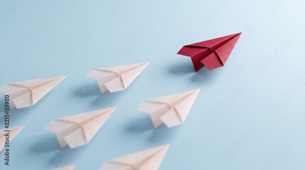 Fototapeta premium Concept of leadership and individuality represented by a single red paper plane leading a group of white paper planes on a blue background, symbolizing business strategy, vision and success.