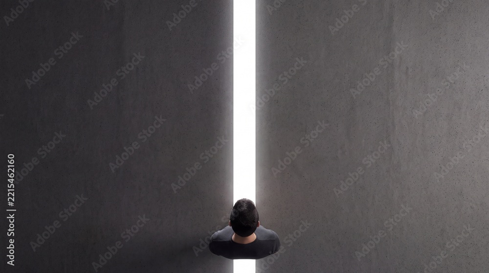 Fototapeta premium Top down view of a man standing in a narrow gap between two massive concrete walls, looking towards a bright white light that symbolizes hope, opportunity, freedom, and a new beginning.