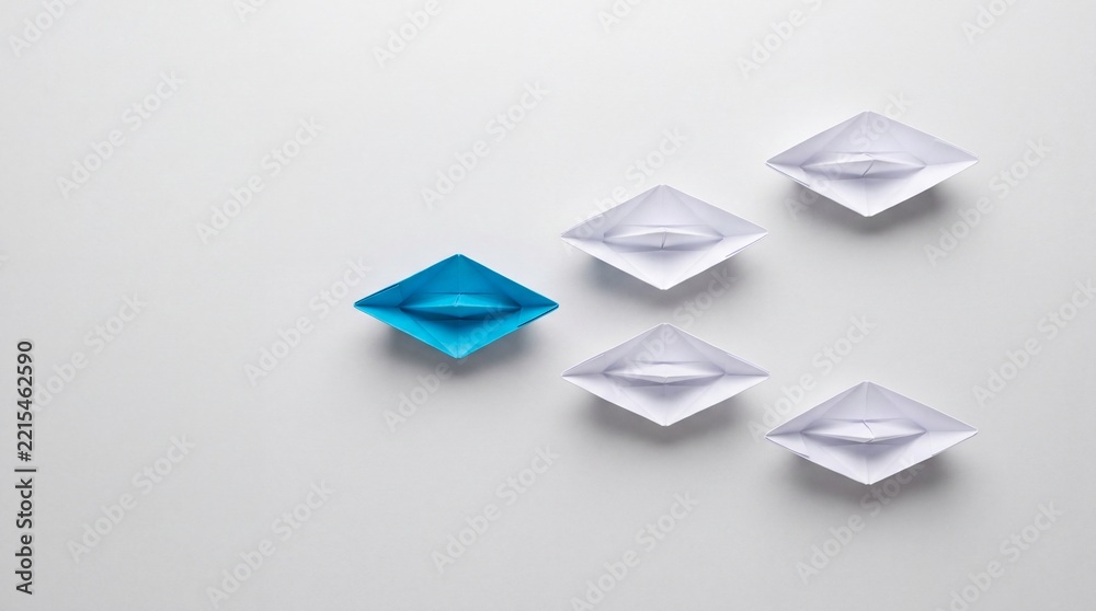 Fototapeta premium Top View of a Single Blue Paper Boat Leading a Group of White Origami Boats on a Clean Surface, Representing Leadership, Business Strategy, Innovation, and Teamwork Success Concept.