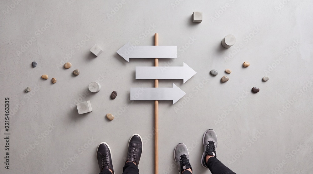 Fototapeta premium Top view overhead shot of two people standing in front of an abstract directional signpost with multiple arrows on grey concrete background, concept of making a choice and career path decision
