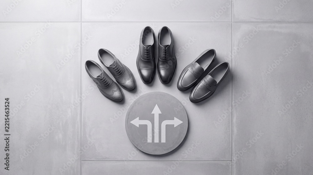 Fototapeta premium Top down view of three pairs of classic men's leather shoes on a grey concrete floor with a circular directional arrow sign representing career choices, decision making, and different life paths.