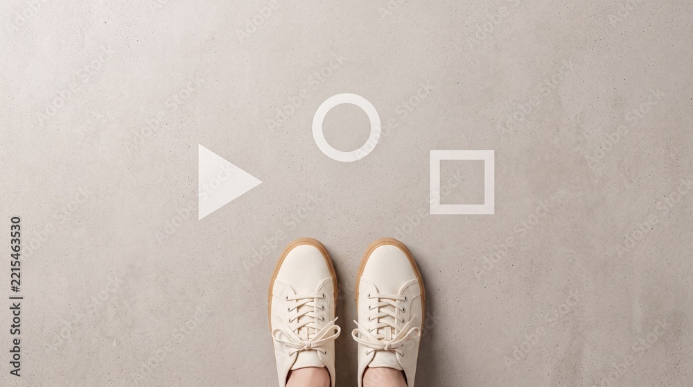 Naklejka premium Top view of a person wearing white sneakers standing in front of white geometric shapes like triangle circle and square on gray concrete ground representing choice decision and career path