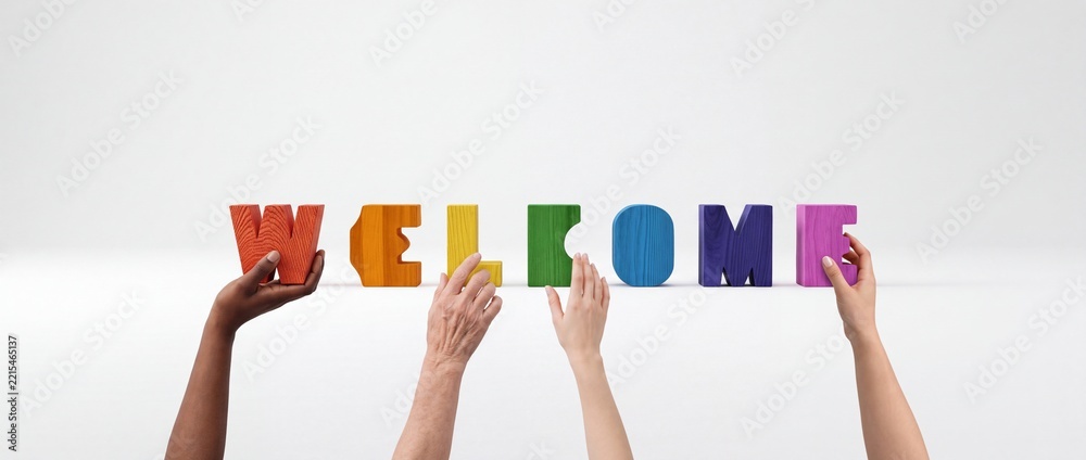 Fototapeta premium Diversity and Inclusion Concept with Multi-ethnic Hands Holding Colorful Wooden Blocks Spelling Welcome Against a Clean White Background for Business and Community Greeting Banners