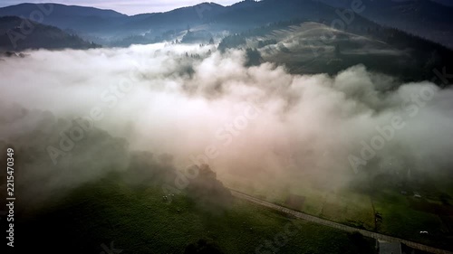 Aerial hyperlapse of dense morning fog rolling over mountain valley with houses