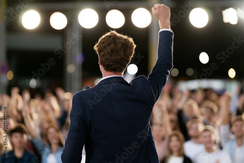 Crowd reacts to speaker during event with raised hands