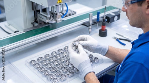 Factory worker inspecting metal components on an assembly line in a lab