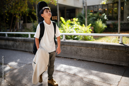 Young boy aspiring to be musician walking with guitar case