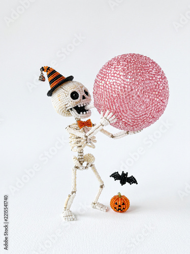 Beaded skeleton in party hat blowing big pink bubblegum bubble