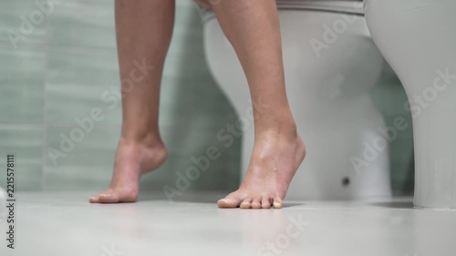 Woman experiencing digestive discomfort while using toilet.