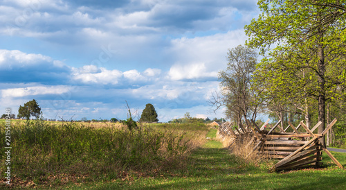 Historic split-rail fence crosses the spring landscape at Gettysburg National Military Park in Pennsylvania on a sunny day