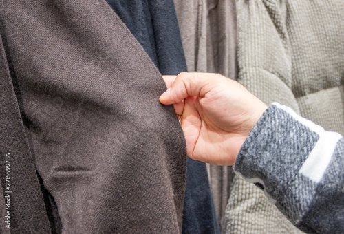 hand holding a sleeve of a blouse, choosing clothes in a store, shopping