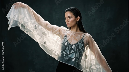 Elegant dancer in patterned costume with flowing fabric against dark studio backdrop