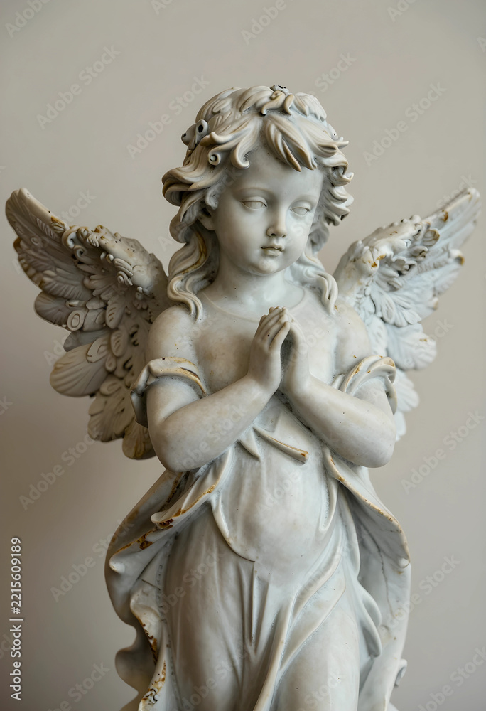Fototapeta premium Spirituality and faith concept marble angel statue with praying hands and wings religious art and peace memorial sculpture for cemetery or garden