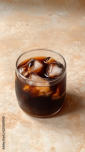 Refreshing glass of cold brew coffee with ice cubes on marble surface