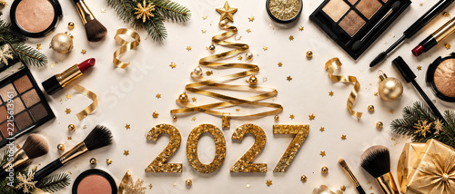 2027 gold glitter numerals surrounded by cosmetics ornaments ribbons and evergreen branches in festive Christmas flat lay arrangement
