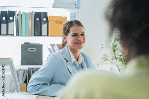 Smiling businesswoman talking with colleague across desk during friendly one on one meeting or job interview in office