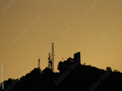 Communication Towers and Ruined Tower on Hilltop at Sunset