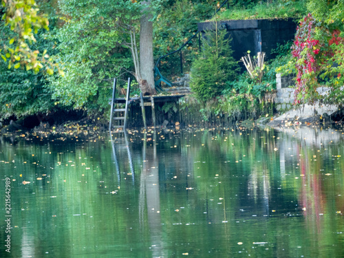 Quiet lake reflects autumn trees and a rustic dock