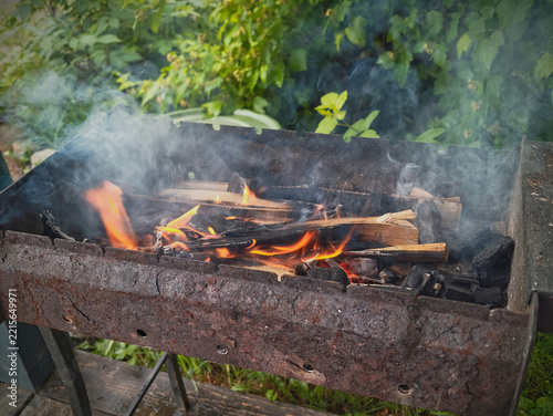iron barbecue grill with burning wood on the porch