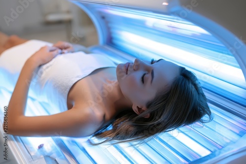 Woman relaxes under bright UV light therapy machine