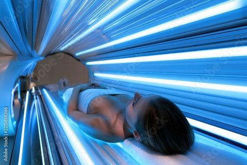 Woman relaxes in tanning bed, eyes closed