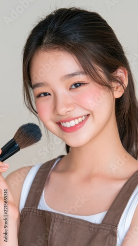Young woman smiles warmly while holding a makeup brush