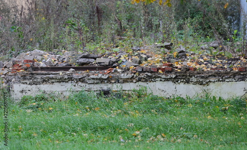 The ruins of the foundation of an old brick wall next to the green lawn