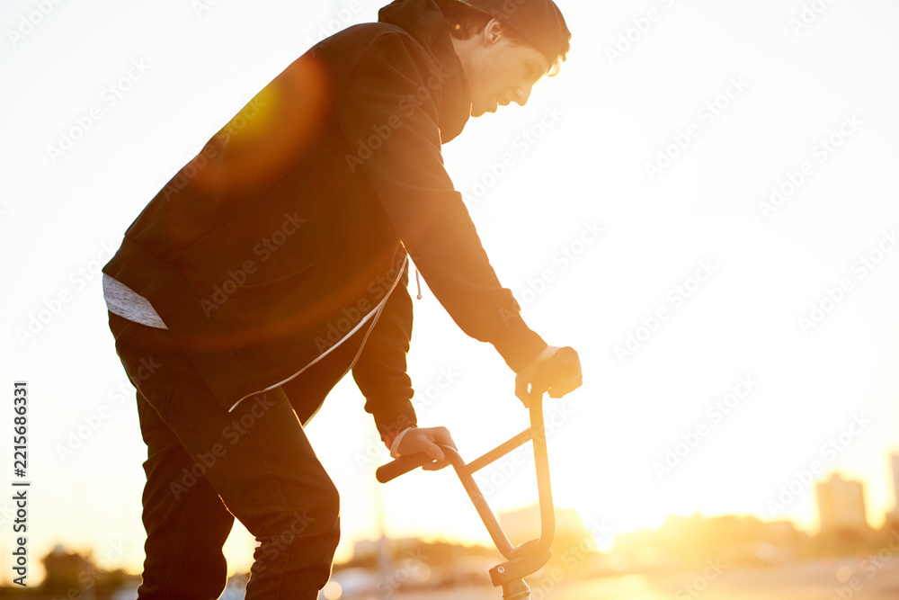 Naklejka premium Balance, city and sunset with man on bicycle for adrenaline, exercise or extreme sports outdoor. BMX, flare and training with bike rider on street in urban town for action, hobby or skill practice