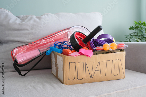 Donation box with sports equipment on the gray sofa