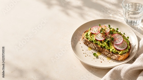 Avocado Toast with Radish Slices and Microgreens on a Cream Ceramic Plate