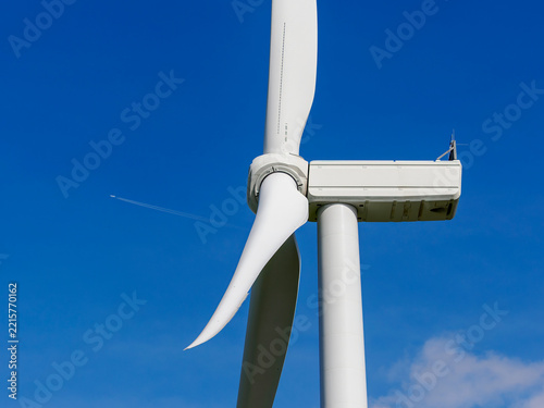 Obraz na plátně Wind turbine generating clean energy under blue sky