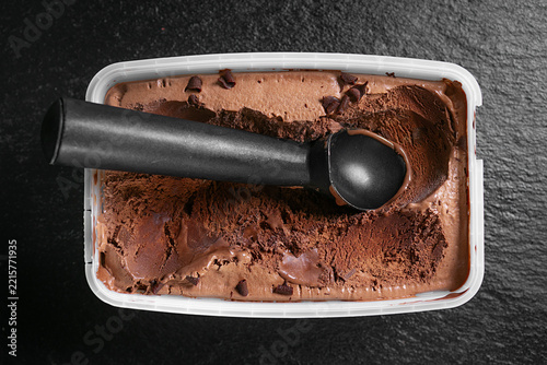 Chocolate ice cream with a scoop in a container.